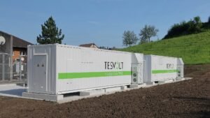 Dois contêineres brancos de um sistema de armazenamento de energia em baterias instalados ao ar livre